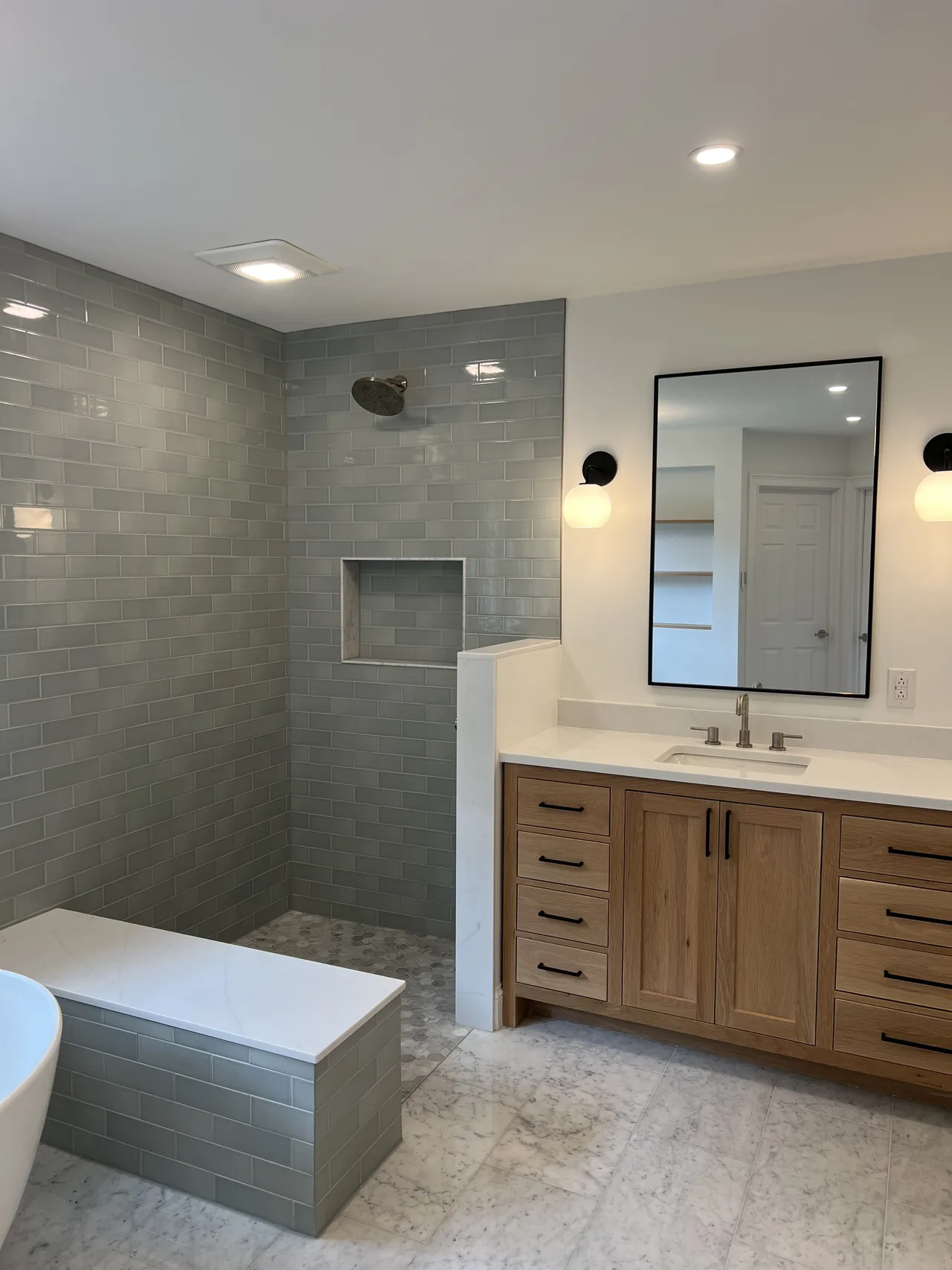 Bathroom with a wood double vanity and blue-gray tiled walk-in shower
