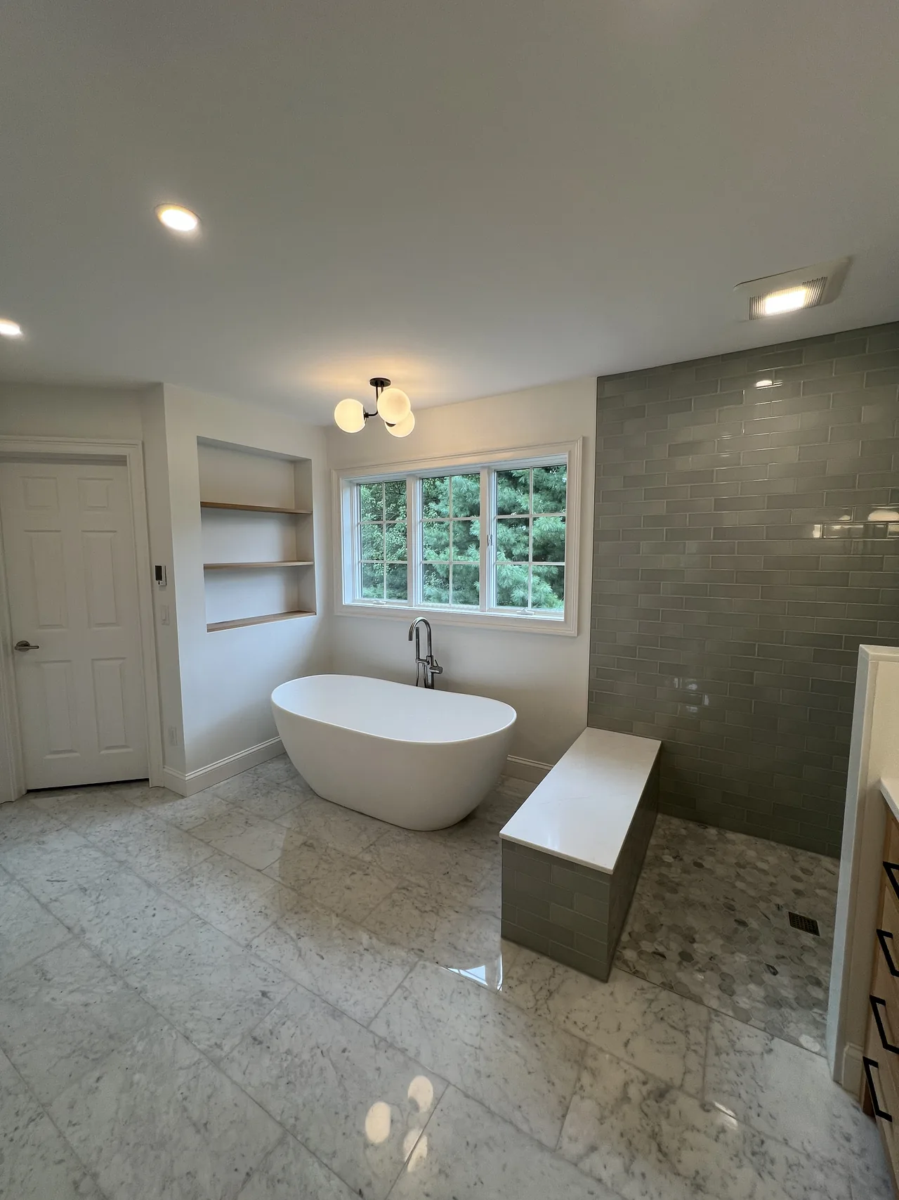 Artifex bathroom renovation with a freestanding tub, tiled shower and natural wood shelving